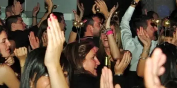Asistentes bailando con los brazos en alto en una fiesta